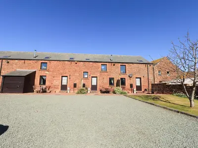 a large brick building with a driveway in front of it at Hayloft Cottage in Wigton