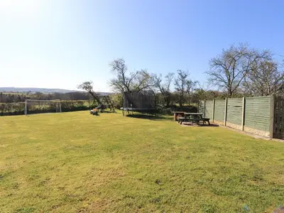 a park with a picnic table and a fence at Horseshoe Cottage in Wigton