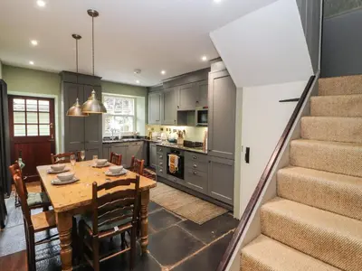 a kitchen and dining room with a table and stairs at 1 Field Foot Cottage in Ambleside