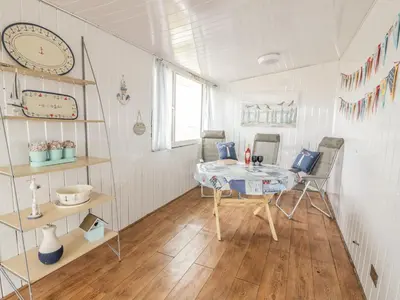 a room with a table and a clock on the wall at Wagtail Cottage in Mainsriddle