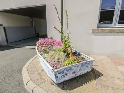 a planter with flowers in it in front of a building at The Moorings in Isle of Whithorn