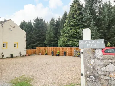a sign in a yard with a fence and trees at The Cottage at Graysondale Farm in Cockermouth