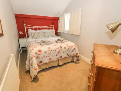 a bedroom with a bed with a red wall at Rowan Cottage in Grasmere