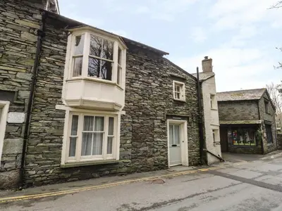 an old stone house with a white window on a street at Rowan Cottage in Grasmere