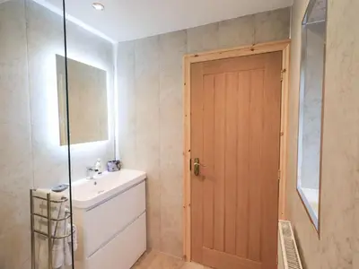 a bathroom with a sink and a wooden door at Rose Cottage in Crosby