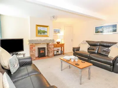a living room with leather furniture and a fireplace at Maple Cottage in Keswick