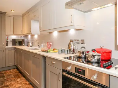 a large kitchen with white cabinets and appliances at Maple Cottage in Keswick