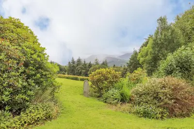 a path through a garden with mountains in the background at Maple Cottage in Keswick
