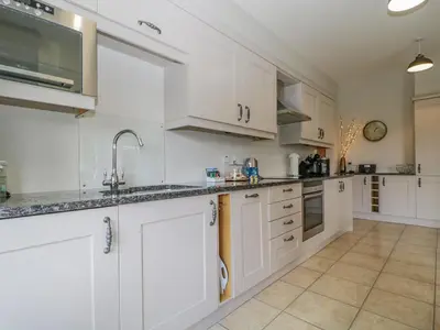 a white kitchen with white cabinets and appliances at Garden Cottage in Keswick