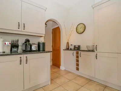 a kitchen with white cabinets and a clock on the wall at Garden Cottage in Keswick