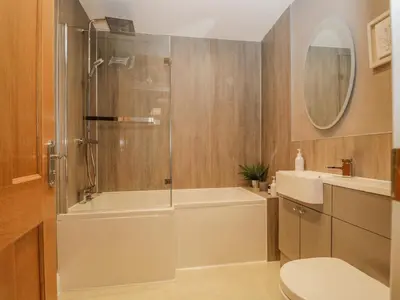 a bathroom with a shower and a tub and a toilet at Garden Cottage in Keswick