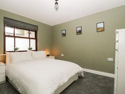 a bedroom with a white bed and green walls at Andra Ghyll in Keswick