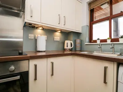 a kitchen with white cabinets and a sink at Andra Ghyll in Keswick