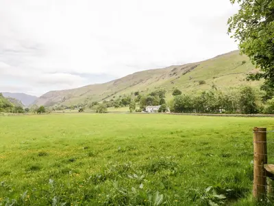 a field with a fence and mountains in the background at Thirlmere Suite in Thirlmere