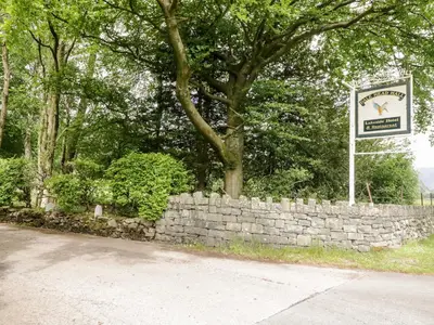 a stone wall with a sign next to a tree at Thirlmere Suite in Thirlmere