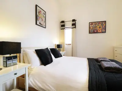 a bedroom with a white bed with a desk and a computer at Keswick Loft in Keswick