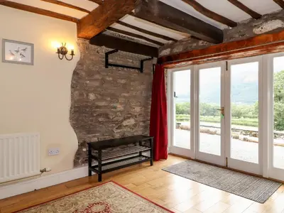 a living room with a stone wall and a window at How End in Braithwaite