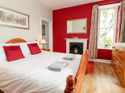 a bedroom with a large bed with red walls and a fireplace at How End in Braithwaite