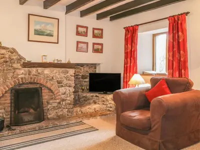 a living room with a couch and a fireplace at Low Garth Cottage in Penruddock