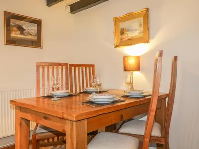 a wooden table with glasses and plates on it at Low Garth Cottage in Penruddock