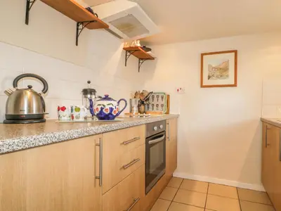 a kitchen with wooden cabinets and a stove at Low Garth Cottage in Penruddock