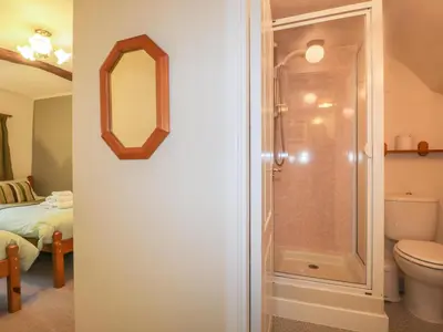 a bathroom with a shower and a toilet with a mirror at Low Garth Cottage in Penruddock