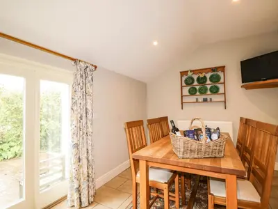 a dining room with a table and chairs and a television at Stockwell Hall Cottage in Sebergham