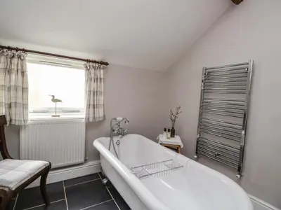 a white bath tub in a bathroom with a window at Stockwell Hall Cottage in Sebergham