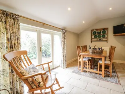 a living room with a table and chairs and a window at Stockwell Hall Cottage in Sebergham