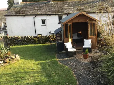 a shed with a bed and two chairs in a yard at Nightingale Cottage in Threlkeld