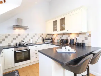 a kitchen with white cabinets and a black counter top at Sky View in Keswick