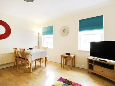 a dining room with a table and chairs and a television at Fox's Den in Keswick