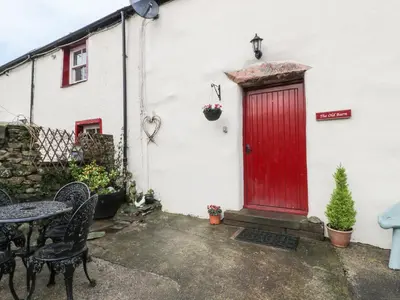 a red door on the side of a white house at The Old Barn in Nether Wasdale
