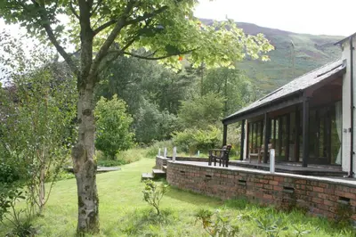 a building with a bench next to a tree at The Byre in Keswick