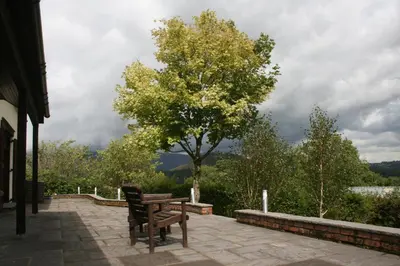 a wooden bench sitting on a patio with a tree at The Byre in Keswick