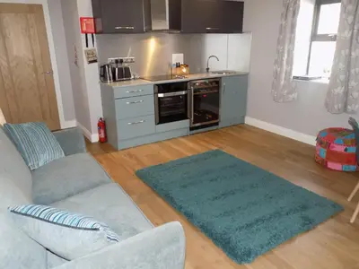 a living room with a couch and a kitchen at The Old Wool House Apartments in Carlisle