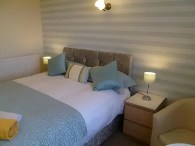 a bedroom with a large bed with blue pillows at Greenlaw Guest House in Gretna Green