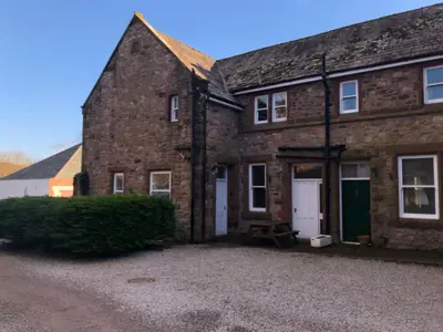 an old brick house with a driveway in front of it at Irton Hall in Eskdale