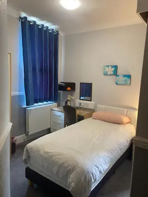 a bedroom with a bed and a desk and a window at Adelphi Guest House in Douglas