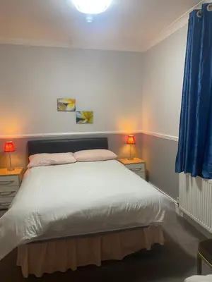 a bedroom with a bed and two night stands with lamps at Adelphi Guest House in Douglas
