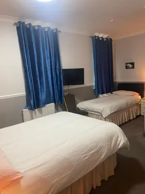 two beds in a room with blue curtains at Adelphi Guest House in Douglas