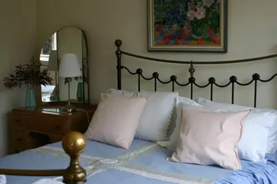 a bedroom with a bed with white pillows and a mirror at Garden Cottage in Prestwick
