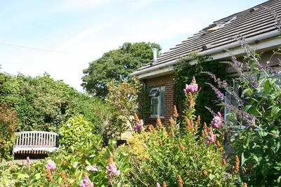 a garden in front of a house with flowers at Garden Cottage in Prestwick