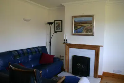 a living room with a blue couch and a fireplace at Garden Cottage in Prestwick
