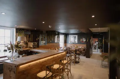 a restaurant with a bar with stools at The Murray Arms Hotel in Gatehouse of Fleet