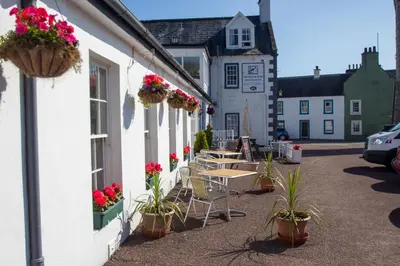 a group of tables and chairs outside of a building at The Murray Arms Hotel in Gatehouse of Fleet