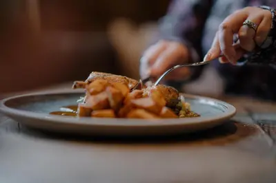 a person eating a plate of food on a table at The Murray Arms Hotel in Gatehouse of Fleet
