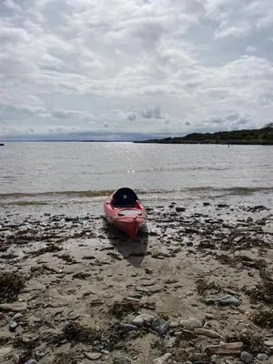 a pink kayak sitting on the shore of a body of water at Jack's Hideaway in Gatehouse of Fleet