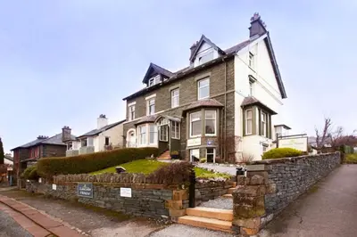 a large house with a stone wall in front of it at Lincoln Guest House in Keswick