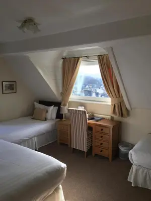 a bedroom with two beds and a desk and a window at Lincoln Guest House in Keswick